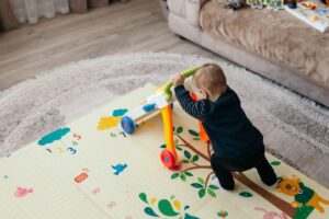 Un jeune enfant joue au sol sur un tapis de motricité coloré.