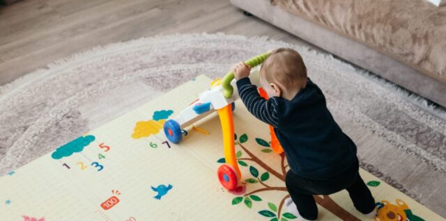 Un jeune enfant joue au sol sur un tapis de motricité coloré.